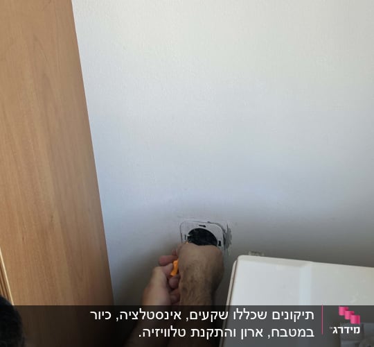 אדם מתקן שקע חשמל עם מברג כתום